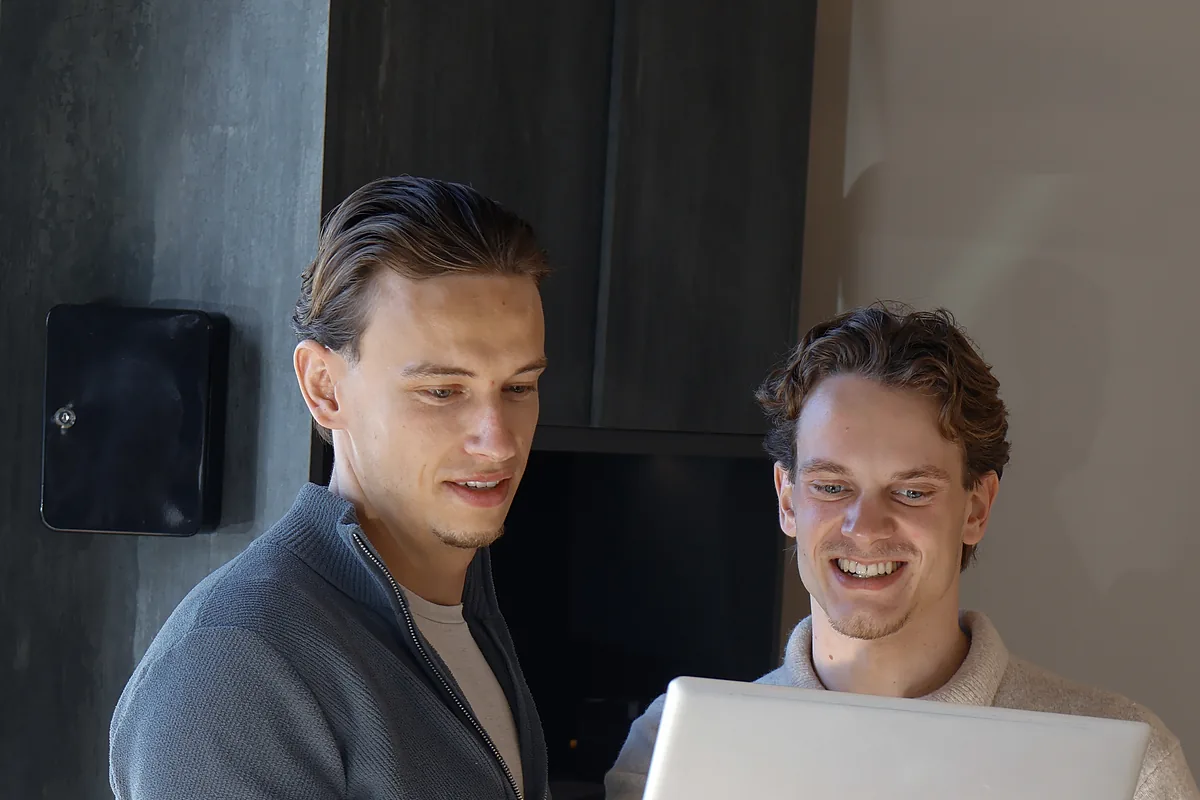 Thomas Benjamins en een collega van de front office kijken samen op een laptop